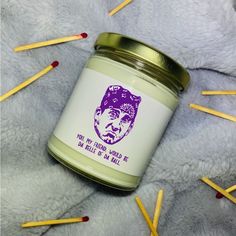 there is a jar of candles with matches on the floor next to it and an image of a man's face