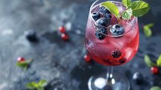 a glass filled with blueberries and mint garnish on top of a table