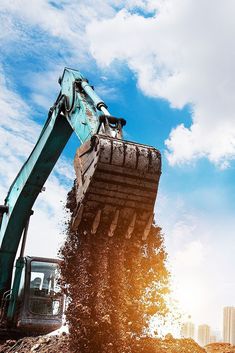 an excavator is dumping dirt onto the ground with it's back end