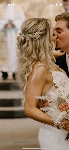 a bride and groom kissing each other in front of a church alter with flowers on it