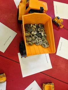 a dump truck filled with rocks on top of a red floor next to white papers