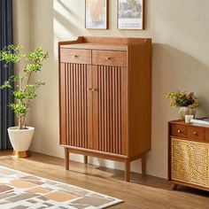 a wooden cabinet sitting on top of a hard wood floor next to a potted plant