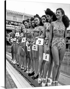 women in bathing suits lined up on the edge of a swimming pool at a sporting event