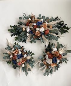 three flowers and leaves are arranged in the shape of wreaths on a white wall