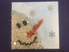 a snowman made out of sea glass and pebbles on a blue background with snowflakes