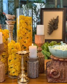 flowers and candles are sitting on display in front of other vases with yellow flowers