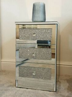 a tall mirrored dresser with drawers and a vase on top of it in a room