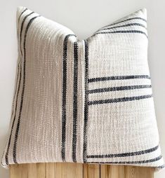 a black and white striped pillow sitting on top of a wooden headboard next to a wall