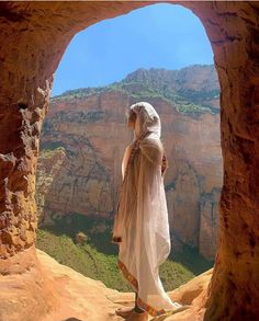 a woman standing on top of a cliff looking out at the mountains and canyons