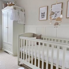 a white crib in a room with pictures on the wall