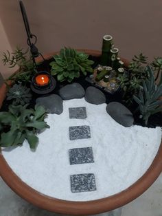 a potted planter filled with rocks and succulents next to a candle