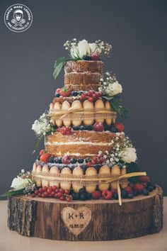 a wedding cake made out of fruit and flowers on top of a tree stump with the word love written below it