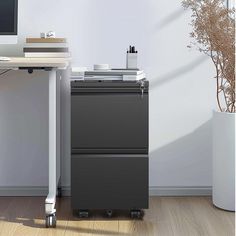 a black filing cabinet sitting in front of a computer desk