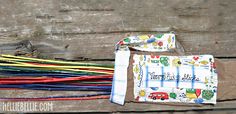 an assortment of colorful toothbrushes on top of a wooden table next to a cloth bag