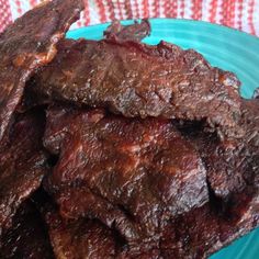 beef strips on a blue plate sitting on a red and white checkered table cloth