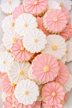 pink and white cookies with flowers on them are arranged in a square plate, ready to be eaten