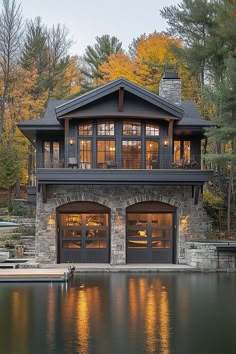 a large house with two garages next to a body of water in front of trees