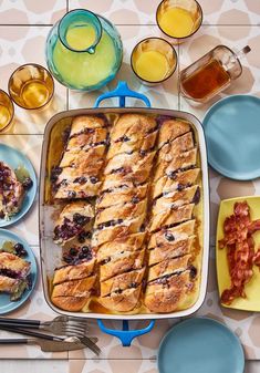 a pan filled with food next to other plates and glasses on a table top,