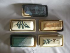 four ceramic trays with designs on them sitting on a white cloth covered tablecloth