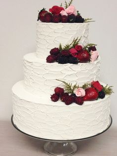 a three tiered white wedding cake with red and pink flowers