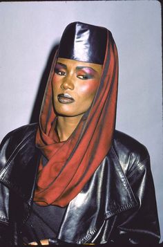 a woman wearing a black leather jacket with a red scarf around her neck and head