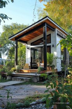 a tiny house is sitting in the middle of some rocks and trees, with a porch on one side