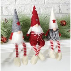 three christmas gnomes sitting on top of a mantle