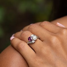 The Story A stunning ring from the 1930s-1950s, filled with sparkle and color. Meeting at center and set askew are a gorgeous natural ruby and Old European cut diamond. The cushion cut ruby weighs 1.44 carats and the chunky old cut diamond weighs 1.15 carats. Working out from the center are four baguettes on top and bottom giving the ring a chic geometric design. This incredible ring has a total diamond weight of approximately 1.61 carats. Done in platinum, the backs are open allowing light to p Heirloom Three Stone Ruby And Diamond Ring, Heirloom Three Stone Ruby Ring With Diamonds, Heirloom Three-stone Ruby And Diamond Ring, Heirloom Three-stone Ruby Ring With Diamonds, Diamond Ruby Ring With Center Stone For Promise, Asscher Cut Ruby Ring With Center Stone For Wedding, Wedding Asscher Cut Ruby Ring With Center Stone, Ruby Ring In Platinum With Round Cut, Promise Ruby Ring With Center Stone