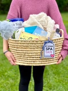 a woman holding a wicker basket filled with books and other items in the grass