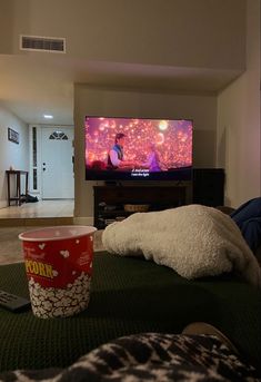 a red cup sitting on top of a rug next to a remote control and television