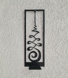 a metal wall hanging on the side of a white building with a black iron design