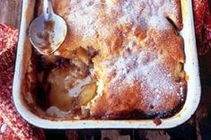 a casserole dish filled with fruit and covered in powdered sugar on top of a wooden table