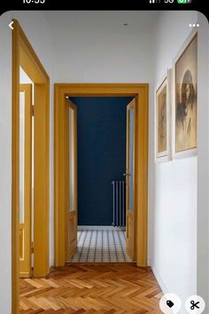 an open door leading to another room with pictures on the wall and wooden flooring