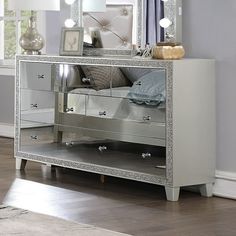 a mirrored dresser with drawers and lights on the top shelf in front of a window