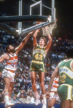 a basketball player is going to dunk the ball in front of two other players