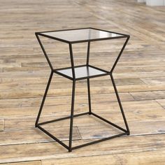 a glass and metal side table sitting on top of a wooden floor