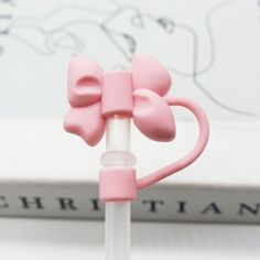 a small pink bow on top of a white stick with a book in the background