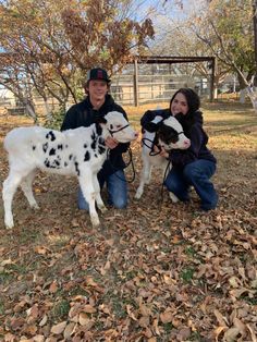 two people kneeling down with their dogs in the leaves