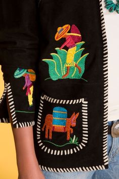 a close up of a person wearing a black jacket with colorful embroidered animals on it