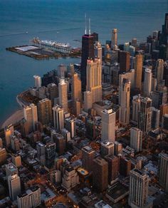 an aerial view of a city with tall buildings and the ocean in the background at dusk