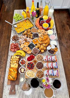 a table filled with lots of food on top of a wooden floor next to bottles of juice