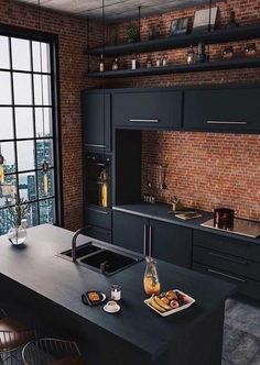 an industrial kitchen with brick walls and black cabinets, stainless steel appliances and counter tops