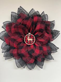 a red and black flower with a deer on it's center, hanging from the wall