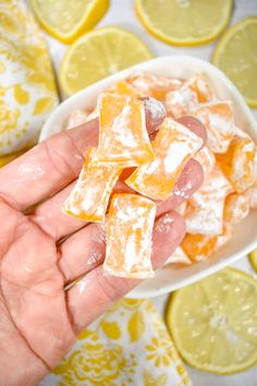 a hand holding a small bowl filled with orange and lemon squares