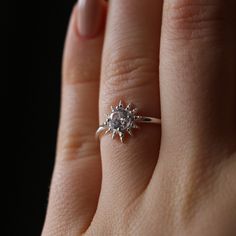 a woman's hand with a diamond ring on top of her finger, showing the center stone