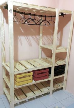 a wooden shelf with clothes hanging from it's sides and two baskets on the bottom