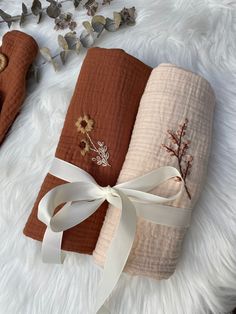 three different colored towels tied together on top of a white furnishing area with flowers and leaves