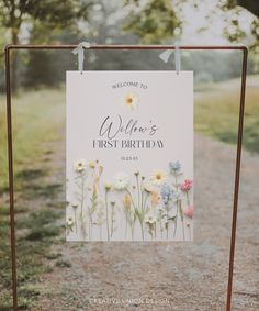 a sign with flowers on it that says welcome to willow's first birthday in front of a dirt path