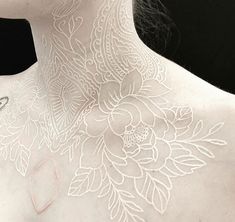 the back of a woman's neck is covered in white lace with flowers on it