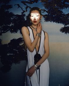 a woman with her face painted like a tree in front of a wallpapered background